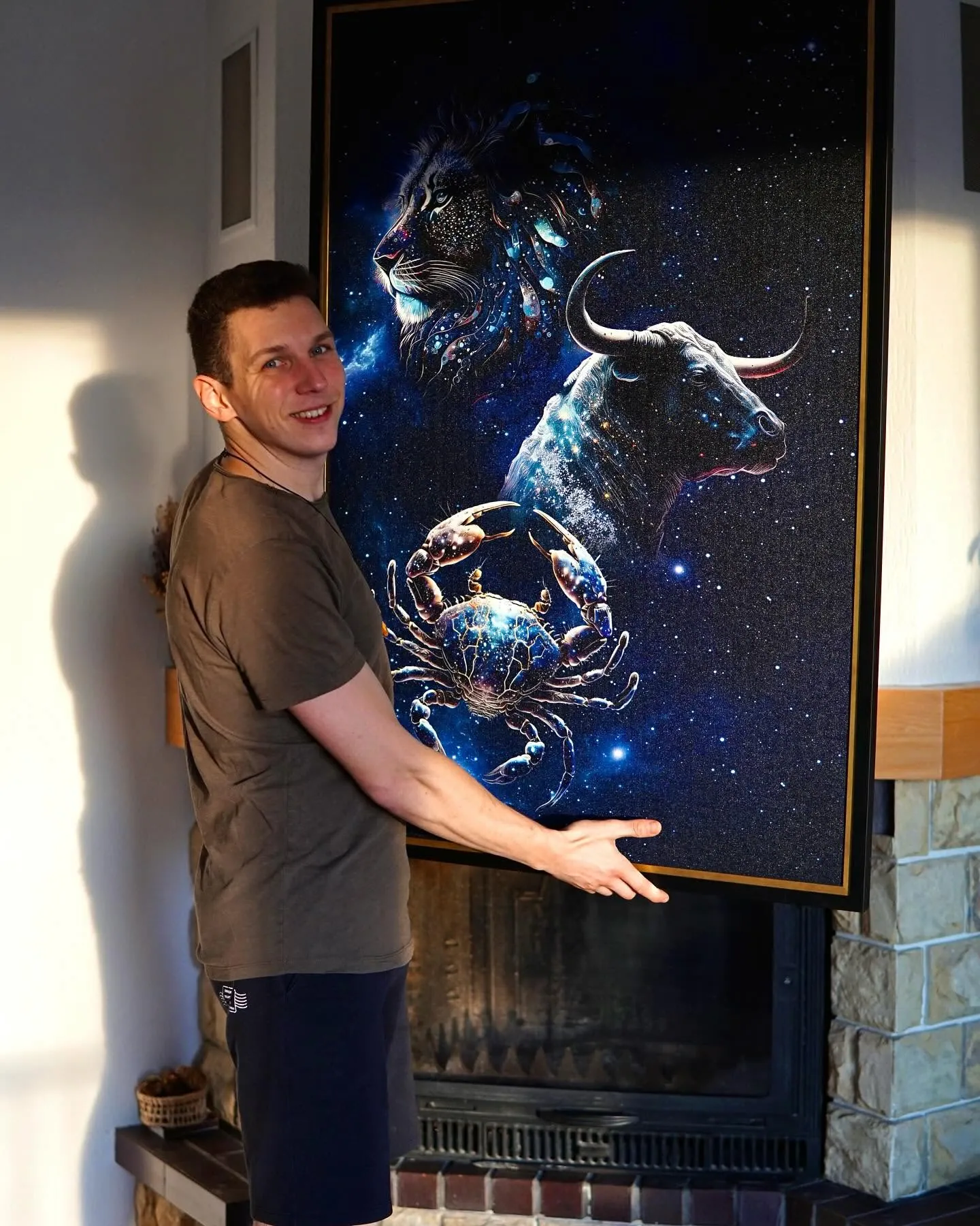 Shapie artist Sarunas holding a large framed zodiac canvas painting featuring a lion, bull and crab.