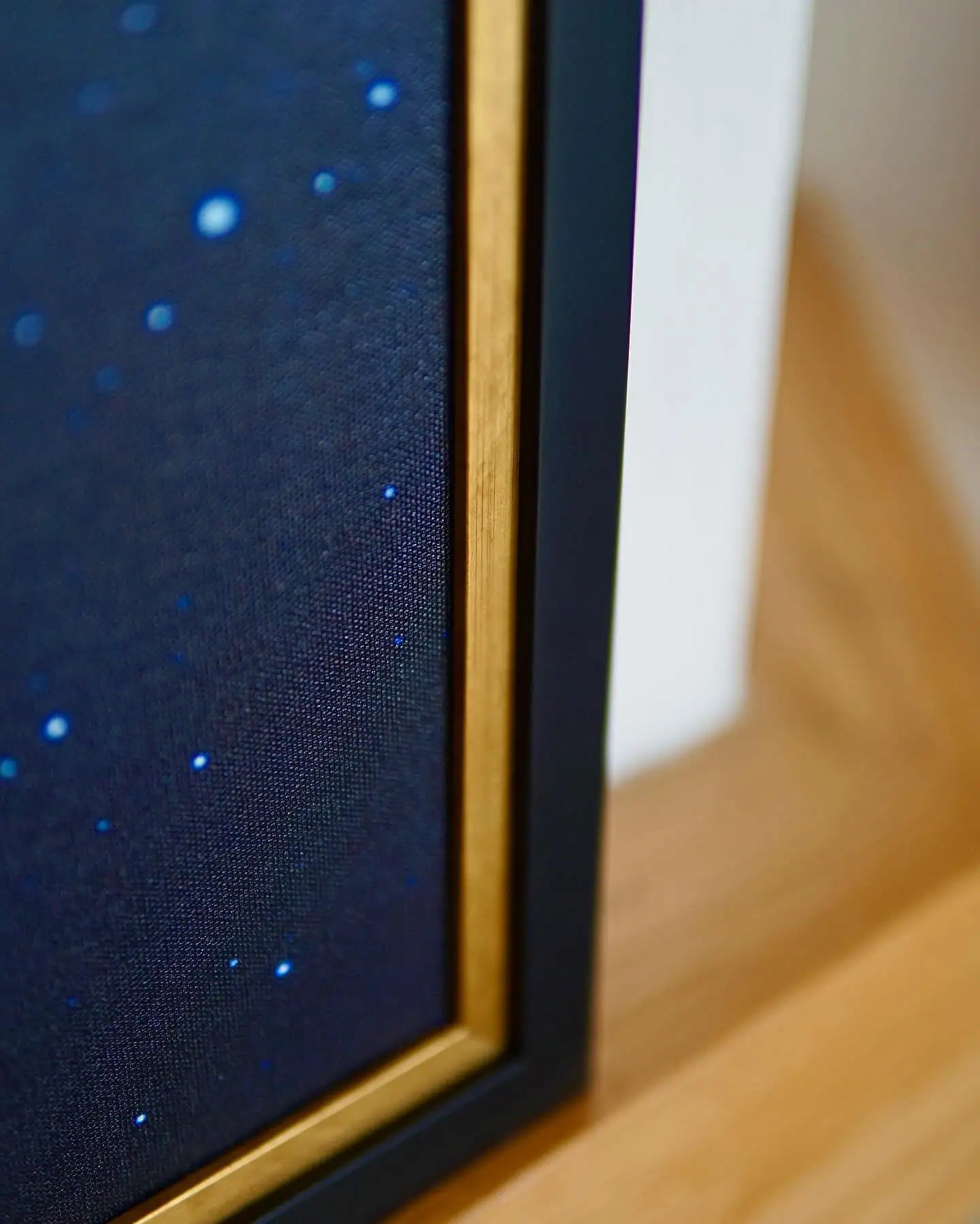 Close-up of the zodiac painting’s textured blue canvas beside its black frame and gold-coloured inner border.