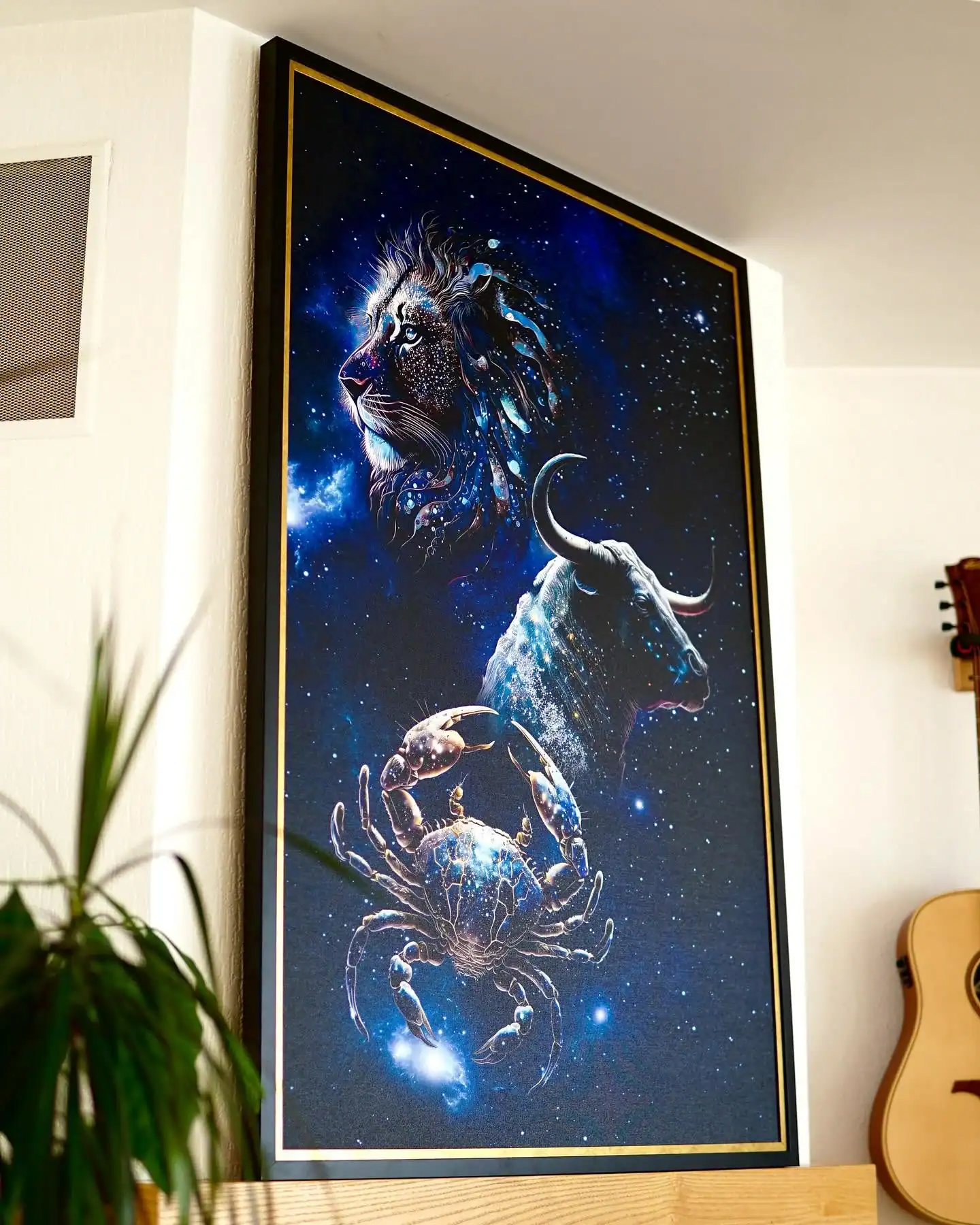 Framed zodiac canvas artwork with a lion, bull and crab against a blue star-filled background, photographed in daylight.